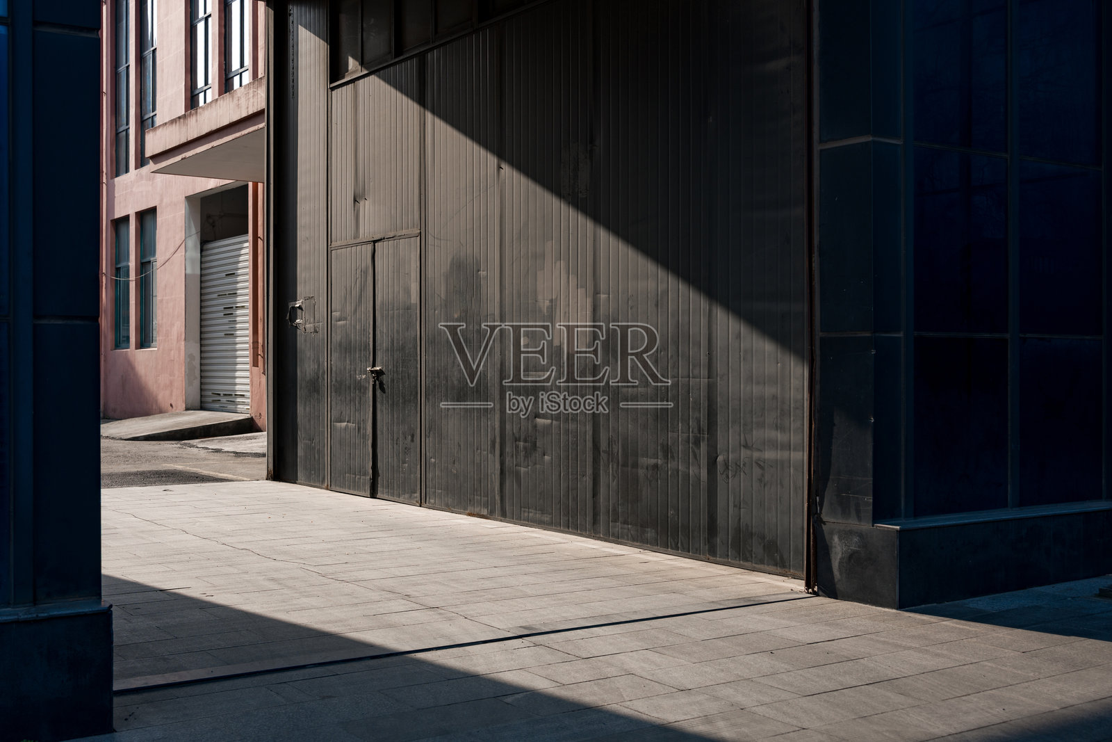 城市巷道光影交错黑色卷帘门街景照片摄影图片