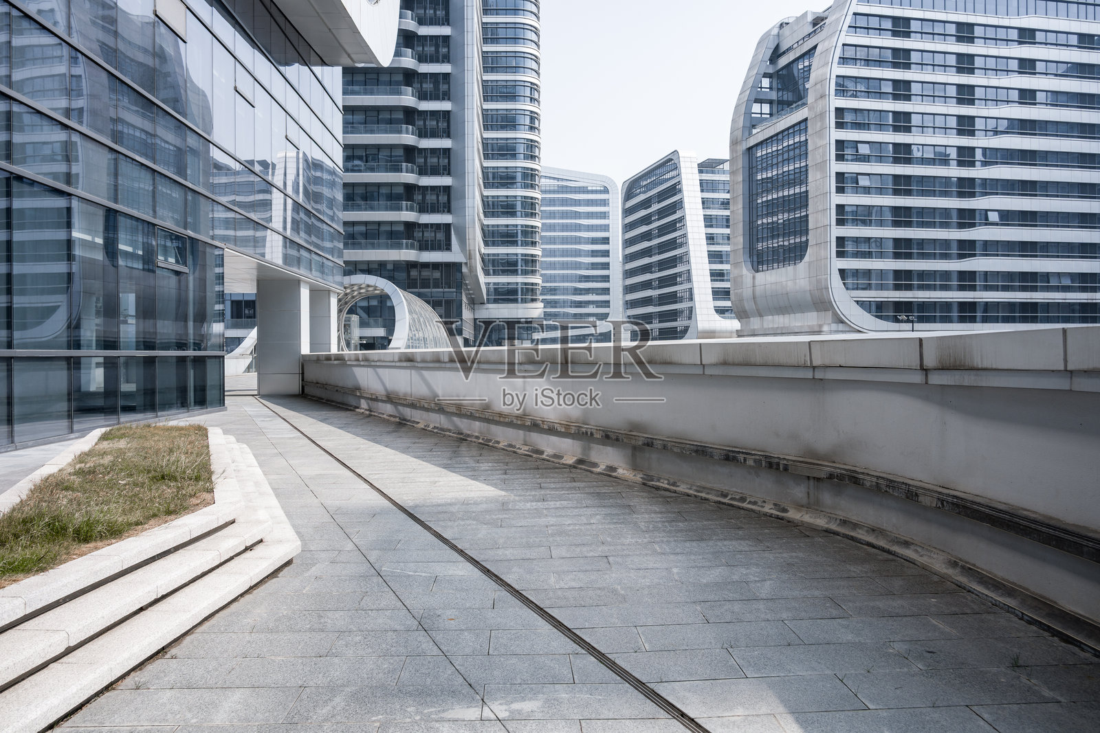 现代建筑群间弧形连廊与玻璃幕墙照片摄影图片