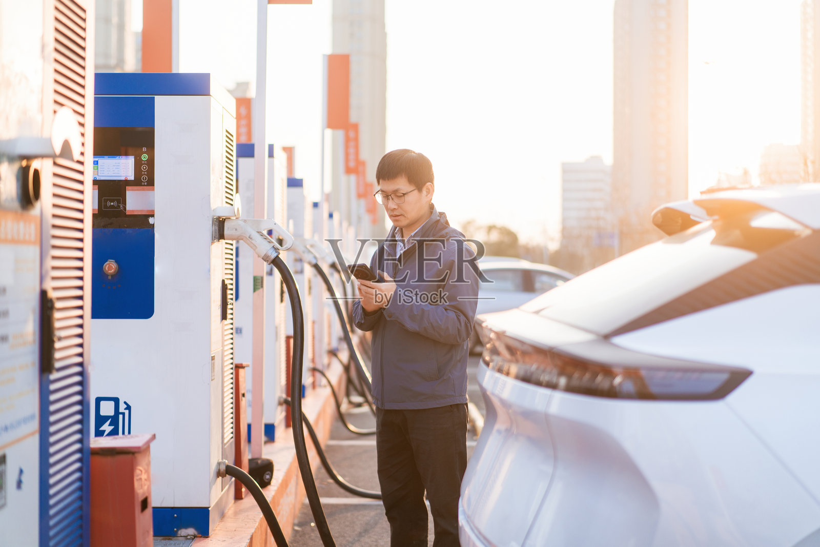 男子在充电桩旁查看手机充电车辆照片摄影图片