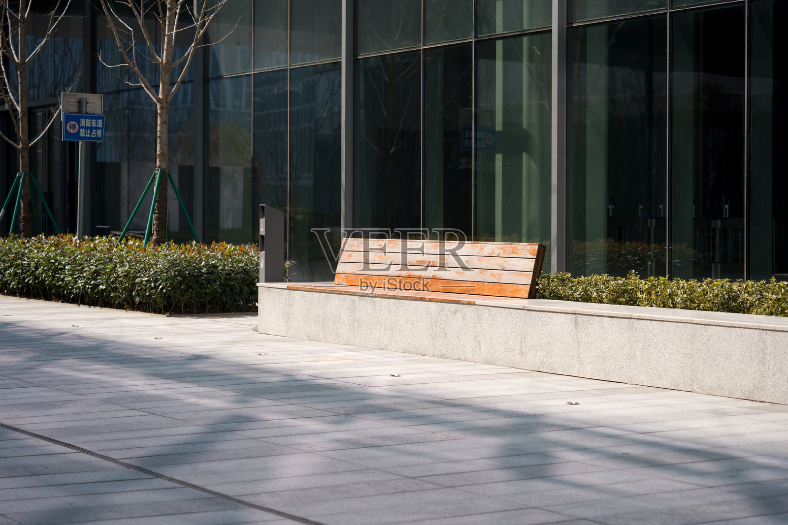 现代玻璃幕墙建筑前空木椅与绿植照片摄影图片