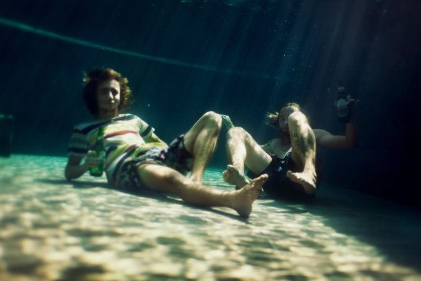 两个年轻人在泳池里喝啤酒图片 两个年轻人在泳池里喝啤酒图片下载