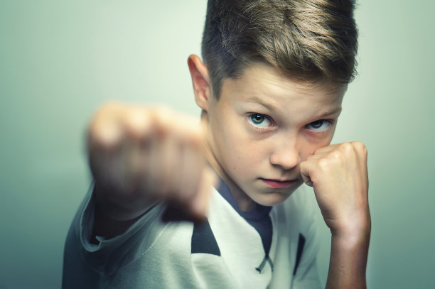 愤怒的小男孩穿着白色t恤训练箱子打拳。图片 愤怒的小男孩穿着白色t恤训练箱子打拳。图片下载