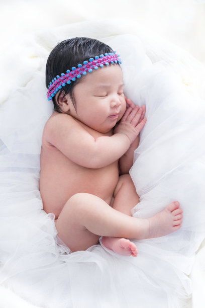 新生的女婴睡在白色的床上,放松,感觉很好,很快乐图片 新生的女婴睡在白色的床上,放松,感觉很好,很快乐图片下载