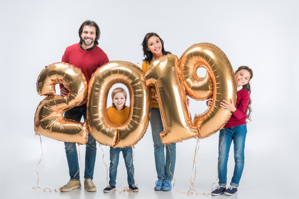 幸福的家庭拿着金色2019标志气球新年和看着相机孤立在白色图片 幸福的家庭拿着金色2019标志气球新年和看着相机孤立在白色图片下载