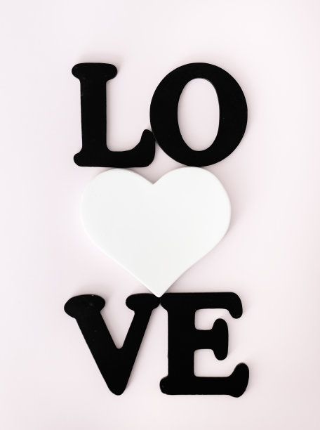 浅粉色背景上的黑色文字“爱”和白色心形情人节概念图片 浅粉色背景上的黑色文字“爱”和白色心形情人节概念图片下载