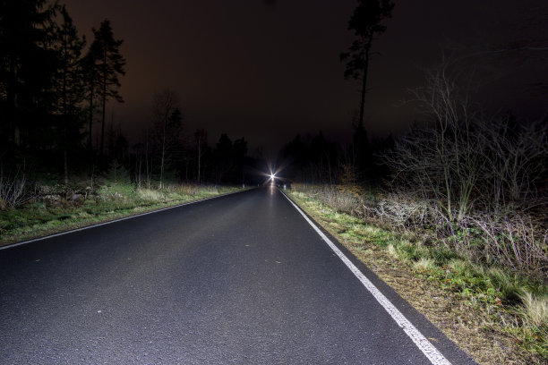 夜间在森林道路上拍摄的汽车照片图片 夜间在森林道路上拍摄的汽车照片图片下载