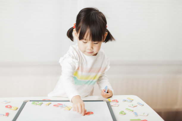 蹒跚学步的小女孩在白色背景下的白板上学习数学图片 蹒跚学步的小女孩在白色背景下的白板上学习数学图片下载