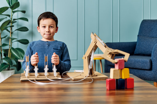一个6-7岁的孩子发明了一个带纸板和注射器的机械手臂。机器人是他的家庭作业。他在小学时是个成功的学生。图片 一个6-7岁的孩子发明了一个带纸板和注射器的机械手臂。机器人是他的家庭作业。他在小学时是个成功的学生。图片下载