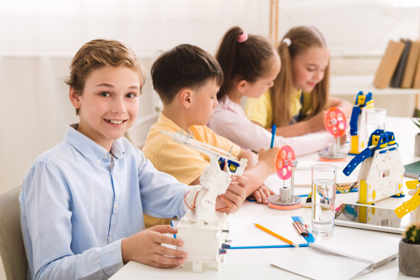 STEM教育:微笑的男学生展示他的机器人图片 STEM教育:微笑的男学生展示他的机器人图片下载