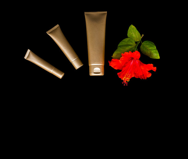 黑色背景上的金色奶油瓶和热带花朵。图片 黑色背景上的金色奶油瓶和热带花朵。图片下载