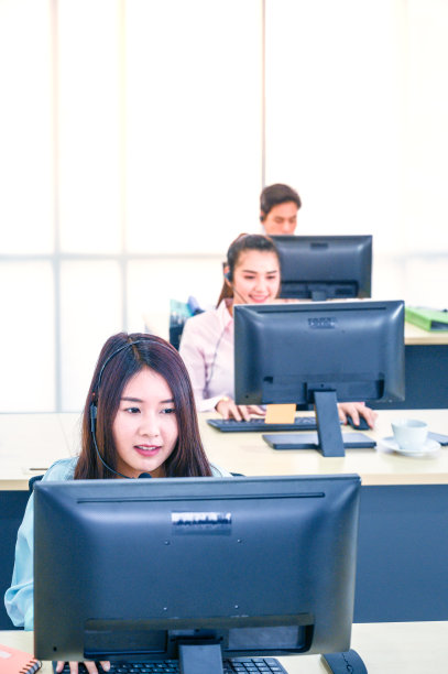 年轻的女客户服务代理,戴着耳机和电脑在办公室工作。图片 年轻的女客户服务代理,戴着耳机和电脑在办公室工作。图片下载