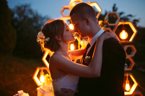 晚上的婚礼。新娘和新郎在婚礼拱门的背景上。图片 晚上的婚礼。新娘和新郎在婚礼拱门的背景上。图片下载
