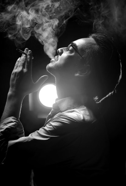 一幅男人的肖像,穿着正式的衬衫,戴着眼镜,仰着头,闭着眼睛,吹着烟。侧视图图片 一幅男人的肖像,穿着正式的衬衫,戴着眼镜,仰着头,闭着眼睛,吹着烟。侧视图图片下载