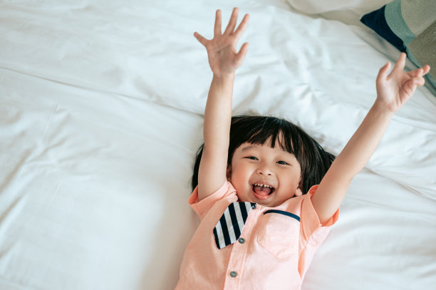 快乐小男孩的肖像欢快的白色卧室。小男孩在床上很快乐。幸福家庭生活理念。图片 快乐小男孩的肖像欢快的白色卧室。小男孩在床上很快乐。幸福家庭生活理念。图片下载