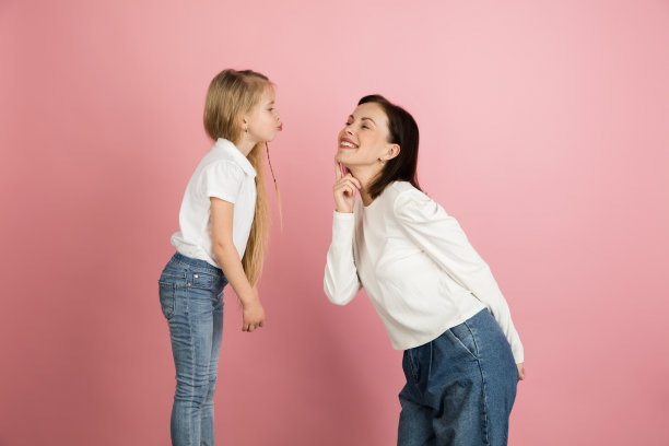 快乐的女人和小女孩,母亲和女儿孤立在粉红色的背景下。图片 快乐的女人和小女孩,母亲和女儿孤立在粉红色的背景下。图片下载