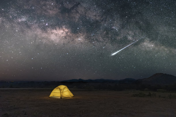 黄色帐篷下的银河与流星在沙漠在泰国北部的乡村,星星上方的夜晚山区森林和一个发光的露营帐篷。图片 黄色帐篷下的银河与流星在沙漠在泰国北部的乡村,星星上方的夜晚山区森林和一个发光的露营帐篷。图片下载