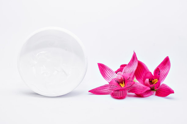 瓶面体润肤霜与粉红色的热带花兰花鸡蛋花在白色的背景图片 瓶面体润肤霜与粉红色的热带花兰花鸡蛋花在白色的背景图片下载