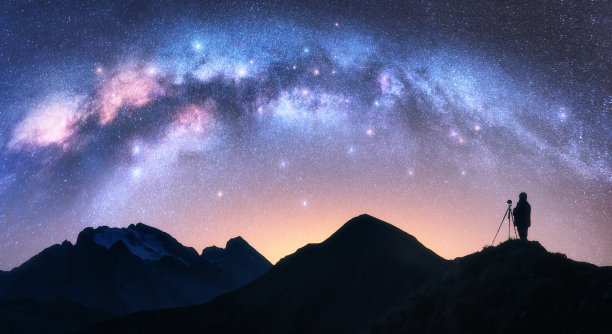拱形的银河和繁星点点的夜晚山上的摄影师。手持三脚架的男子剪影正在与星空合影。星系。空间景观与guy,银河拱门,黄色灯光。自然图片 拱形的银河和繁星点点的夜晚山上的摄影师。手持三脚架的男子剪影正在与星空合影。星系。空间景观与guy,银河拱门,黄色灯光。自然图片下载