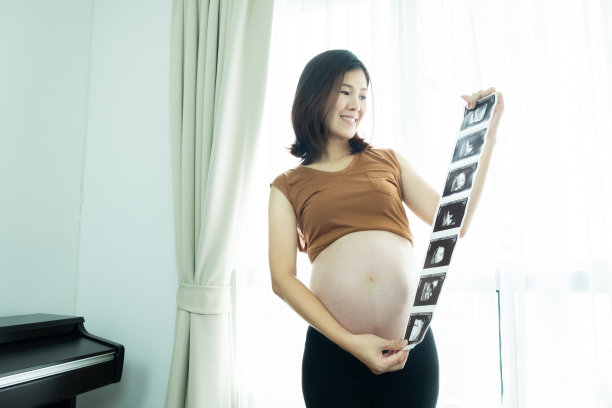 美丽的孕妇抱着看她的婴儿超声波扫描打印。图片 美丽的孕妇抱着看她的婴儿超声波扫描打印。图片下载