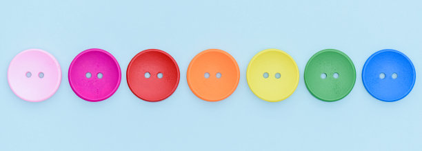 彩色的木制彩虹缝纫按钮在一排浅蓝色的背景。图片 彩色的木制彩虹缝纫按钮在一排浅蓝色的背景。图片下载