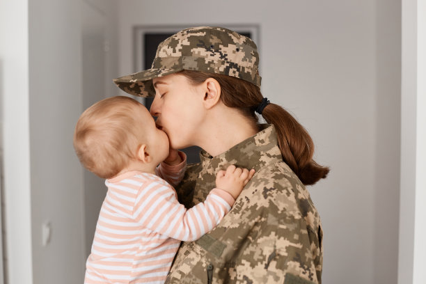 可爱的年轻成年女子士兵穿着迷彩服,回家拥抱她可爱的小女儿,亲吻婴儿,在军队服役后回家。图片 可爱的年轻成年女子士兵穿着迷彩服,回家拥抱她可爱的小女儿,亲吻婴儿,在军队服役后回家。图片下载