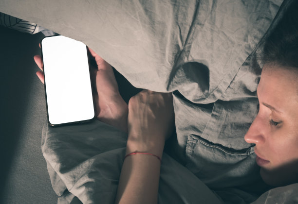 一名女子在床上睡着了,手里拿着智能手机图片 一名女子在床上睡着了,手里拿着智能手机图片下载