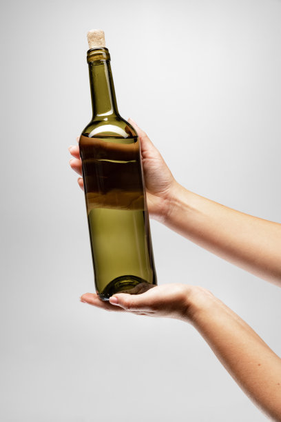 裁剪图像的女性手握一瓶美味的葡萄酒孤立的灰色背景图片 裁剪图像的女性手握一瓶美味的葡萄酒孤立的灰色背景图片下载