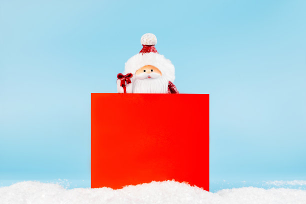 副本的空间。圣诞家居装饰。简单的简约。圣诞老人手里拿着礼物,拿着一个蓝色背景的画框。新年贺卡的背景。图片 副本的空间。圣诞家居装饰。简单的简约。圣诞老人手里拿着礼物,拿着一个蓝色背景的画框。新年贺卡的背景。图片下载