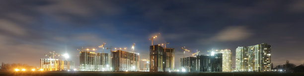 大型建筑工地的景象,有正在施工的建筑物和多层住宅。塔吊在夜空背景下活动。全景。图片 大型建筑工地的景象,有正在施工的建筑物和多层住宅。塔吊在夜空背景下活动。全景。图片下载