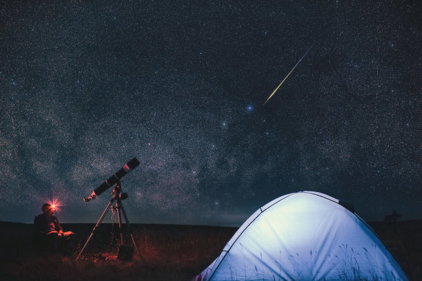 业余天文学家拿着天文望远镜在大自然中露营在银河系的恒星下。图片 业余天文学家拿着天文望远镜在大自然中露营在银河系的恒星下。图片下载