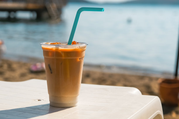 海滩上的塑料杯冰拿铁咖啡。图片 海滩上的塑料杯冰拿铁咖啡。图片下载
