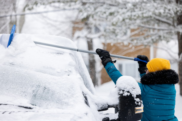 一名年轻女子在暴风雪后清理车上的积雪图片 一名年轻女子在暴风雪后清理车上的积雪图片下载