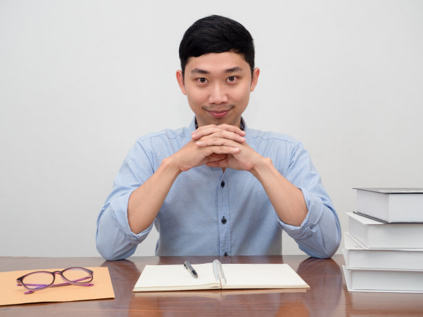 积极的亚洲商人坐在工作桌旁,开心地微笑着,自信地看着你图片 积极的亚洲商人坐在工作桌旁,开心地微笑着,自信地看着你图片下载