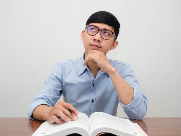 亚洲人戴着眼镜,坐在桌子前工作,姿势思考图片 亚洲人戴着眼镜,坐在桌子前工作,姿势思考图片下载