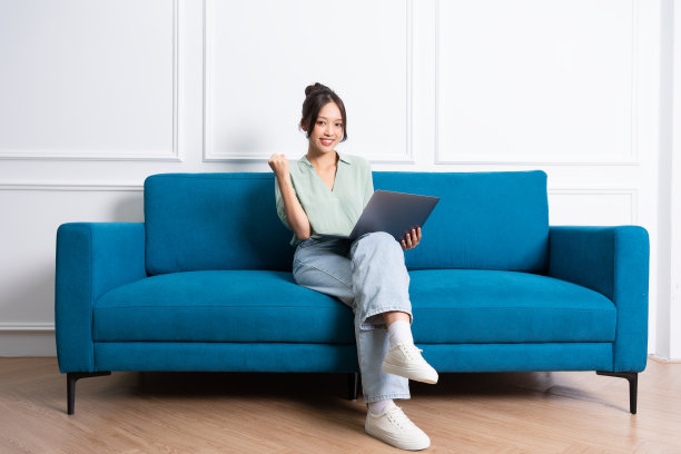 年轻的亚洲女孩坐在家里的沙发上的形象图片 年轻的亚洲女孩坐在家里的沙发上的形象图片下载