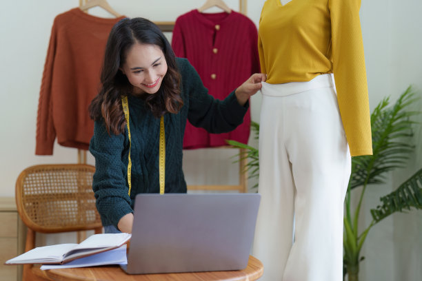 亚洲女性时装设计师布裁缝创意工作的新系列。快乐的网上商店老板准备运输订单图片 亚洲女性时装设计师布裁缝创意工作的新系列。快乐的网上商店老板准备运输订单图片下载