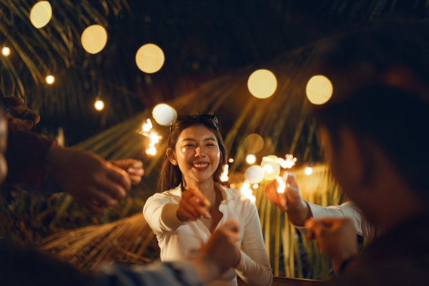 快乐的亚洲妇女与她的朋友们在户外庆祝节日的晚会上玩烟花。图片 快乐的亚洲妇女与她的朋友们在户外庆祝节日的晚会上玩烟花。图片下载