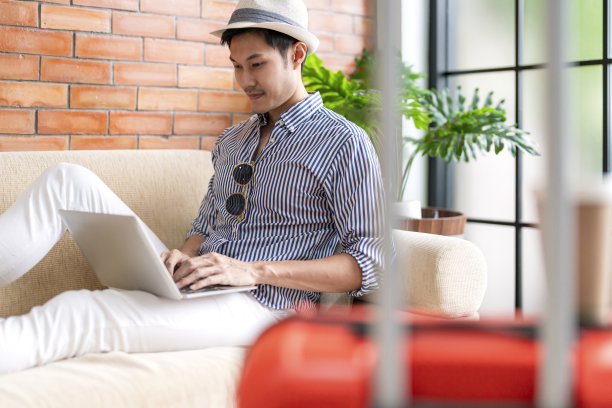 亚洲男子数字游牧民手拿笔记本电脑在酒店大堂等待航班时刻表,准备旅行亚洲男子游客微笑愉快坐在酒店大堂的沙发上图片 亚洲男子数字游牧民手拿笔记本电脑在酒店大堂等待航班时刻表,准备旅行亚洲男子游客微笑愉快坐在酒店大堂的沙发上图片下载