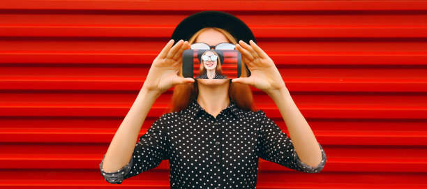 近距离的现代年轻女子伸出她的手用智能手机在红色背景上自拍图片 近距离的现代年轻女子伸出她的手用智能手机在红色背景上自拍图片下载