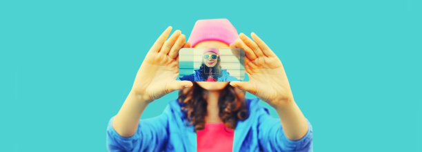 近距离的现代年轻女子伸出她的手在蓝色背景上用智能手机自拍图片 近距离的现代年轻女子伸出她的手在蓝色背景上用智能手机自拍图片下载