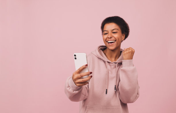 兴奋开朗的非洲女孩使用智能手机,感觉快乐。图片 兴奋开朗的非洲女孩使用智能手机,感觉快乐。图片下载