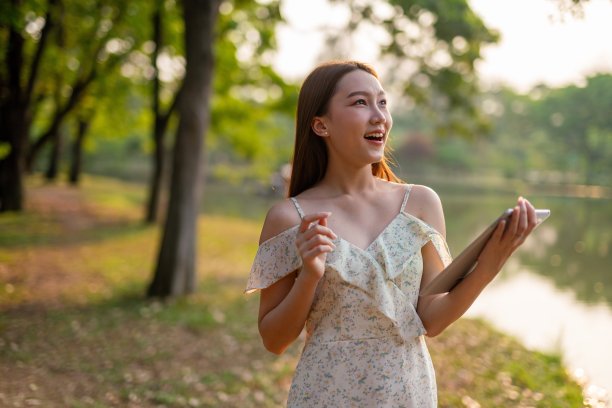 美丽的亚洲女人在公园里玩她的数码平板电脑。在户外工作的年轻女性,一个数字游民图片 美丽的亚洲女人在公园里玩她的数码平板电脑。在户外工作的年轻女性,一个数字游民图片下载