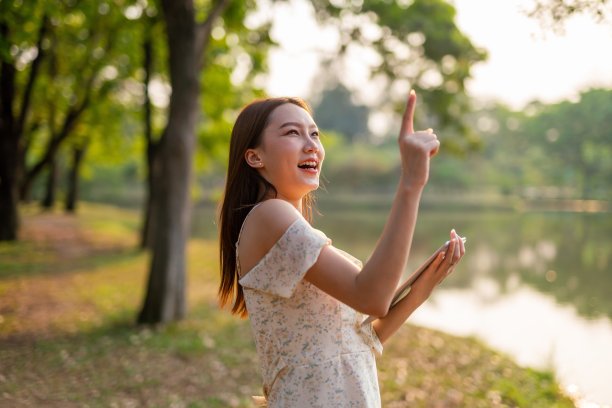 美丽的亚洲女人在公园里玩她的数码平板电脑。在户外工作的年轻女性,一个数字游民图片 美丽的亚洲女人在公园里玩她的数码平板电脑。在户外工作的年轻女性,一个数字游民图片下载