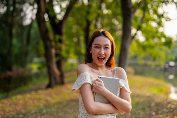 美丽的亚洲女人在公园里玩她的数码平板电脑。在户外工作的年轻女性,一个数字游民图片 美丽的亚洲女人在公园里玩她的数码平板电脑。在户外工作的年轻女性,一个数字游民图片下载