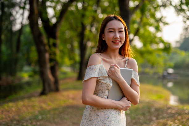 美丽的亚洲女人在公园里玩她的数码平板电脑。在户外工作的年轻女性,一个数字游民图片 美丽的亚洲女人在公园里玩她的数码平板电脑。在户外工作的年轻女性,一个数字游民图片下载