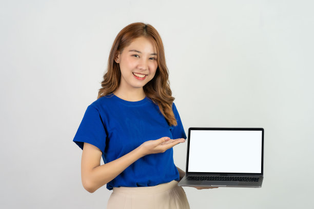快乐微笑的年轻亚洲女性穿着蓝色衬衫拿着笔记本电脑的工作孤立在白色背景的工作室肖像图片 快乐微笑的年轻亚洲女性穿着蓝色衬衫拿着笔记本电脑的工作孤立在白色背景的工作室肖像图片下载