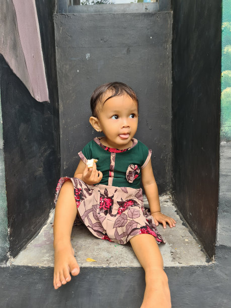 一个印度尼西亚的小女孩早上坐在房子的前廊上吃蛋糕的照片图片 一个印度尼西亚的小女孩早上坐在房子的前廊上吃蛋糕的照片图片下载