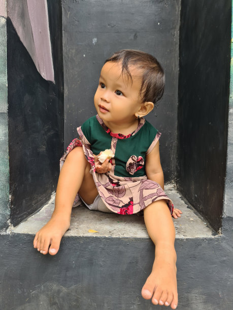 一个印度尼西亚的小女孩早上坐在房子的前廊上吃蛋糕的照片图片 一个印度尼西亚的小女孩早上坐在房子的前廊上吃蛋糕的照片图片下载