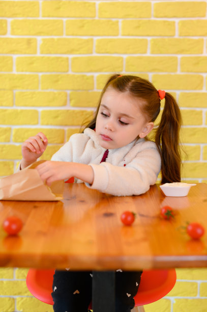 一个可爱的小女孩在快餐店吃薯条的照片。图片 一个可爱的小女孩在快餐店吃薯条的照片。图片下载