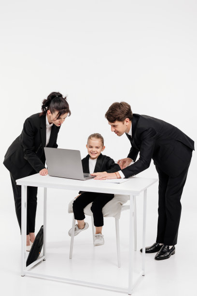 商务小女孩穿着时髦的西装,和成年下属一起坐在办公桌前拿着笔记本电脑。团队合作,风格和财务理念。图片 商务小女孩穿着时髦的西装,和成年下属一起坐在办公桌前拿着笔记本电脑。团队合作,风格和财务理念。图片下载